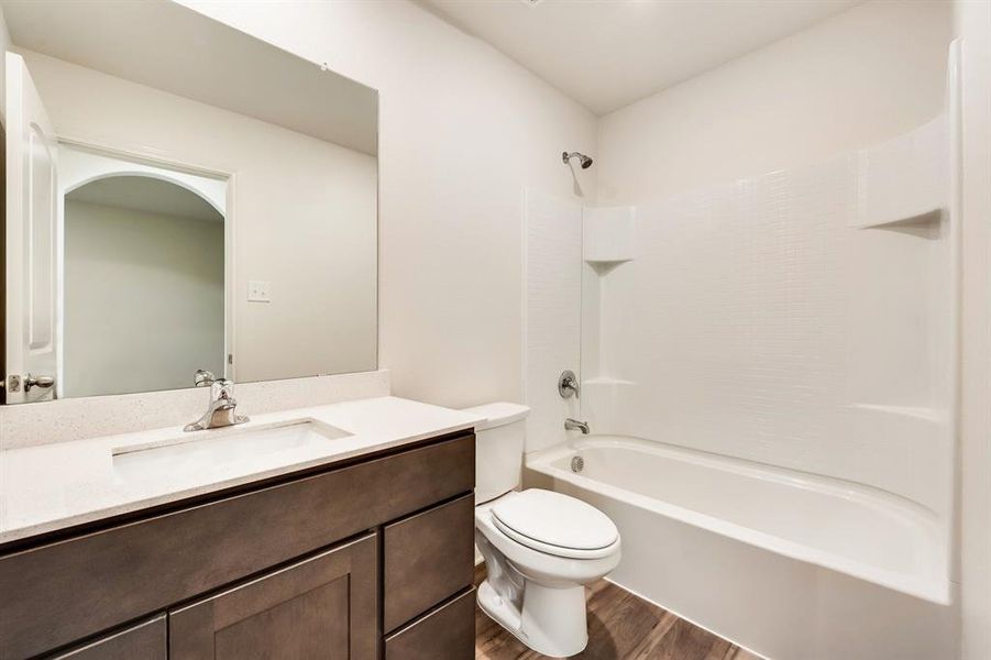 Full bathroom featuring washtub / shower combination, toilet, vanity, and hardwood / wood-style flooring