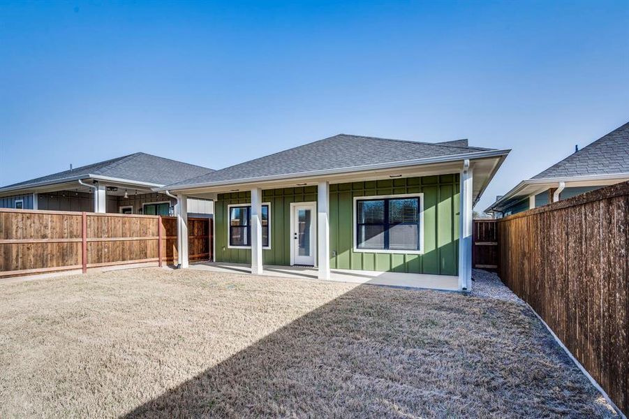 Rear view of house with a fenced backyard, board and batten siding, a shingled roof, and a patio area Rear view of house with a fenced backyard, board and batten siding, a shingled roof, and a patio area