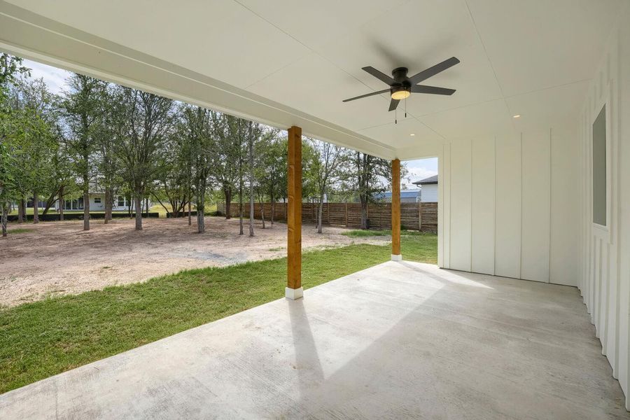 A spacious covered patio invites outdoor relaxation, overlooking a private yard with mature trees.