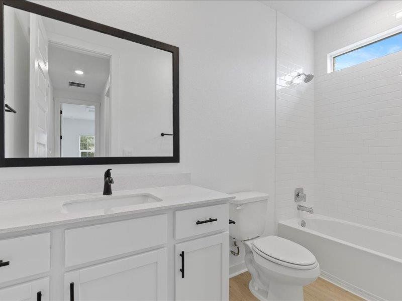 Full bath featuring healthy amount of natural light, shower / bathtub combination, vanity, and light wood finished floors