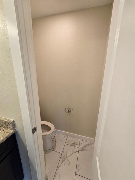 Bathroom featuring marble finish floors, vanity, toilet, and baseboards