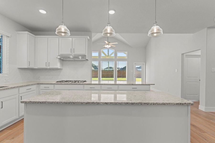 Pendant lighting highlights the island and open design, while natural light streams through large windows overlooking the backyard. Every detail in this San Marcos kitchen has been thoughtfully crafted for everyday luxury.