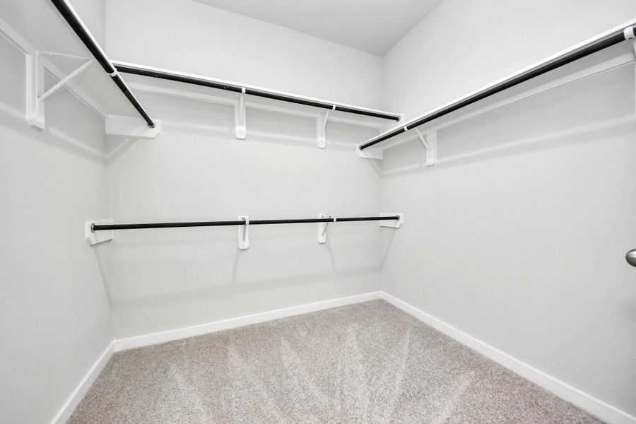 Walk-in closet that epitomizes luxury and practicality. This generously sized space features built-in shelving, offering abundant room for impeccable organization. High ceilings and recessed lighting create a bright and welcoming ambiance. Sample photo of completed home with similar floor plan. Actual colors and selections may vary.