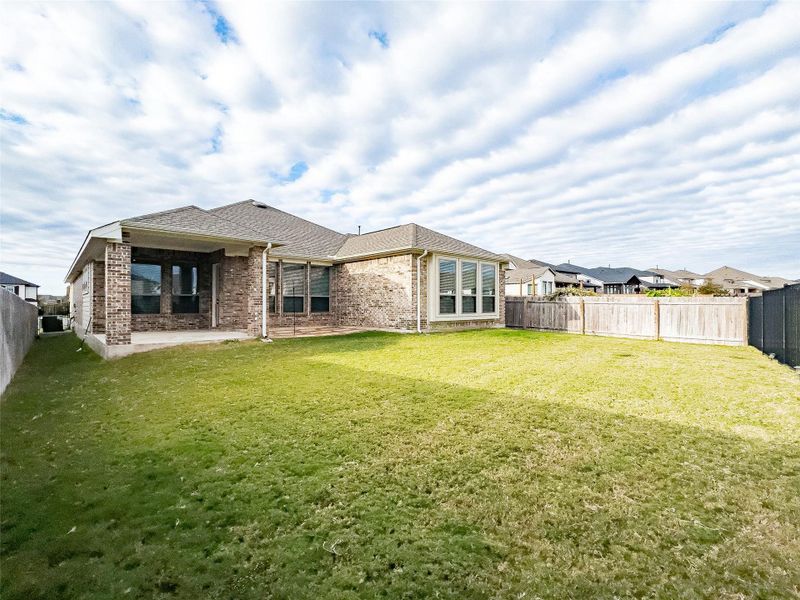 Rear view of house with a fenced backyard, a patio area, brick siding, and roof with shingles Rear view of house with a fenced backyard, a patio area, brick siding, and roof with shingles