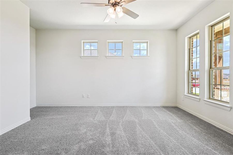 Empty room with carpet, ceiling fan, and plenty of natural light