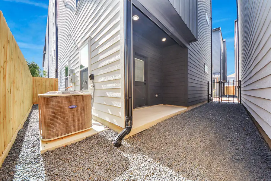This functional side yard features gravel ground cover, a wooden fence, and an outdoor air conditioning unit. A gated entry provides secure access, making the space practical and well-maintained for utility needs. This functional side yard features gravel ground cover, a wooden fence, and an outdoor air conditioning unit. A gated entry provides secure access, making the space practical and well-maintained for utility needs.