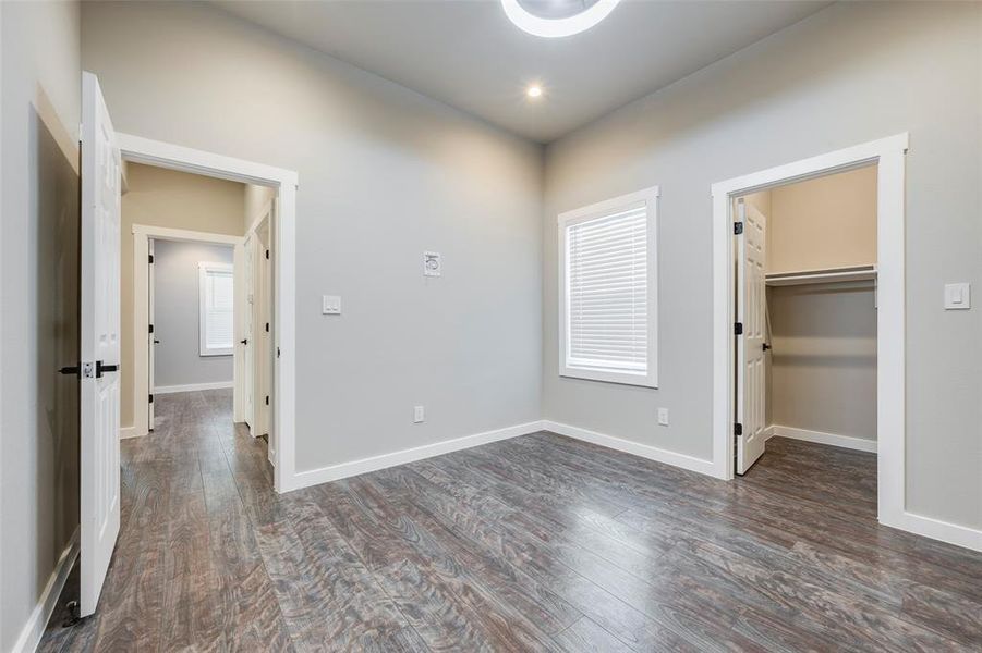 Unfurnished bedroom with a spacious closet and dark wood-style floors
