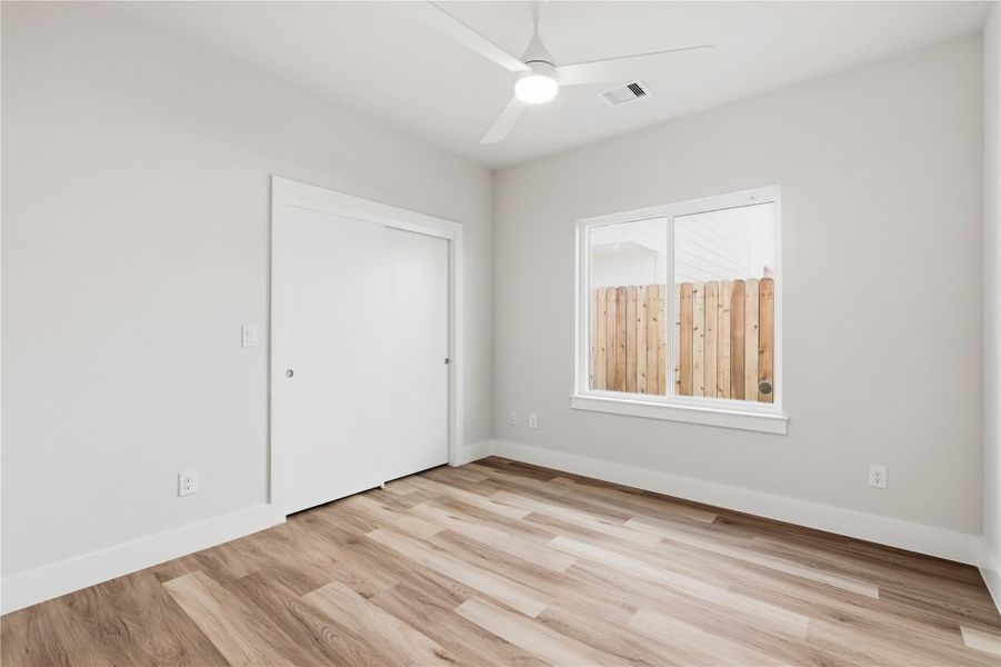 A well-proportioned secondary bedroom featuring LVP flooring, a ceiling fan, and ample natural light, ideal for guests, a home office, or flex space.