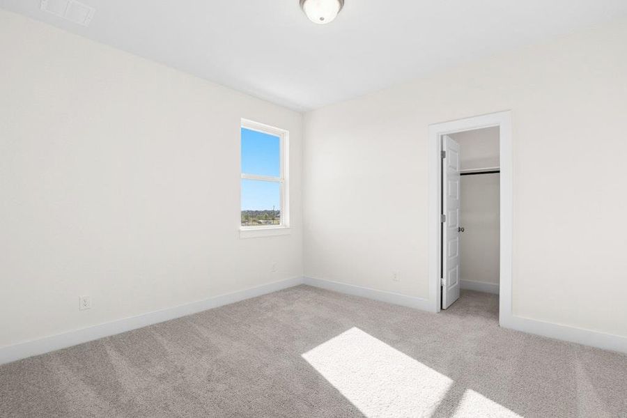 Unfurnished bedroom featuring a spacious closet and light carpet Unfurnished bedroom featuring a spacious closet and light carpet