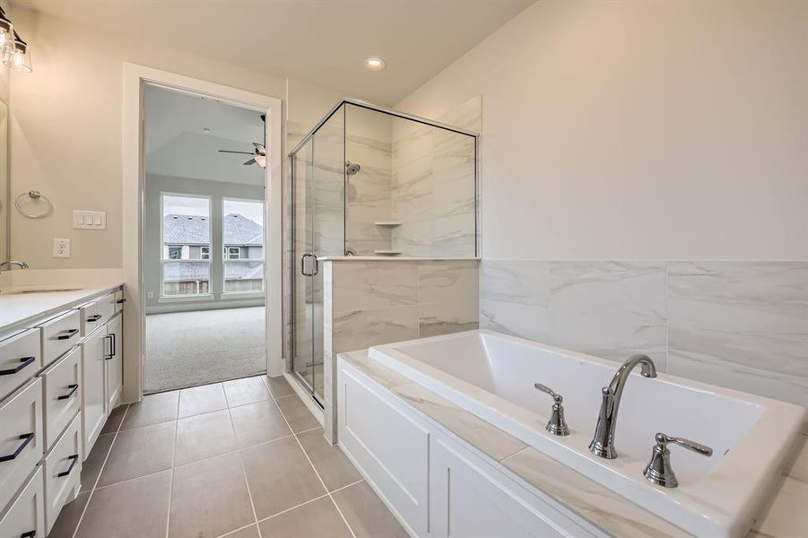 Bathroom with a bath, vanity, a stall shower, ceiling fan, and tile patterned floors