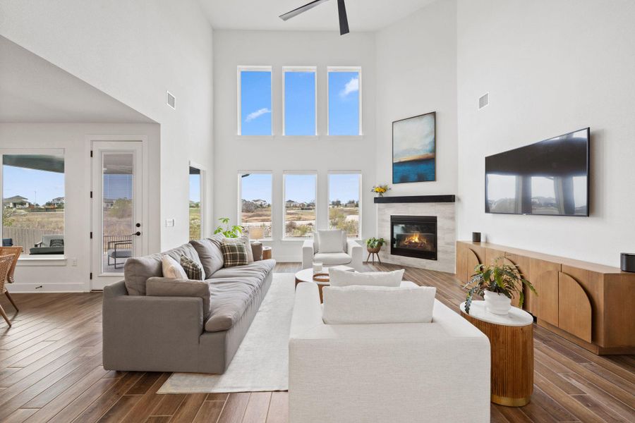 Living area featuring a high ceiling, fireplace, pretty tiled floors, ceiling fan and open and bright.