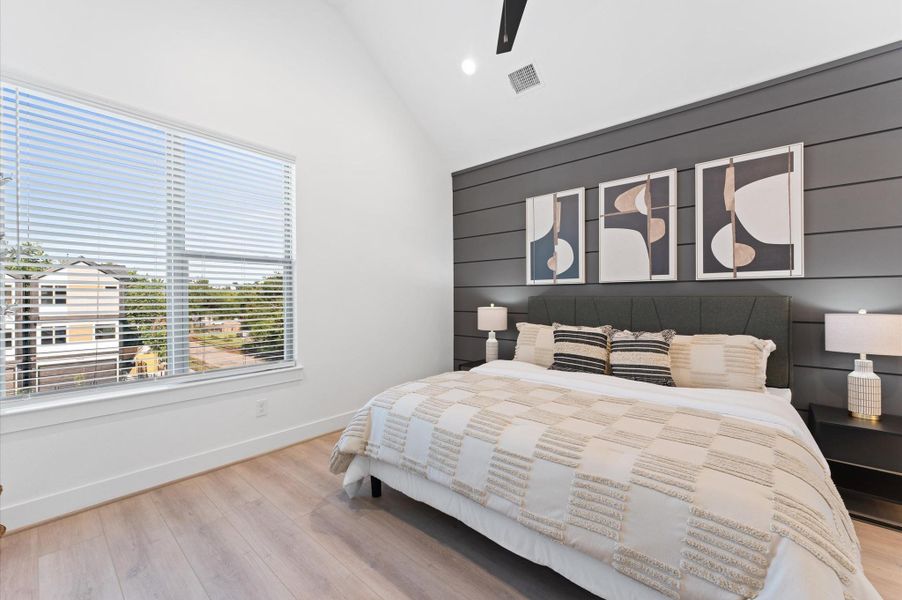 Bright and airy bedroom featuring vaulted ceilings, modern fan, and stylish decor, offering a serene and inviting atmosphere.