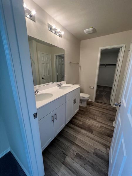 Dual vanities, shower, and wood-look tile flooring create a refreshing bathroom space. Chrome fixtures