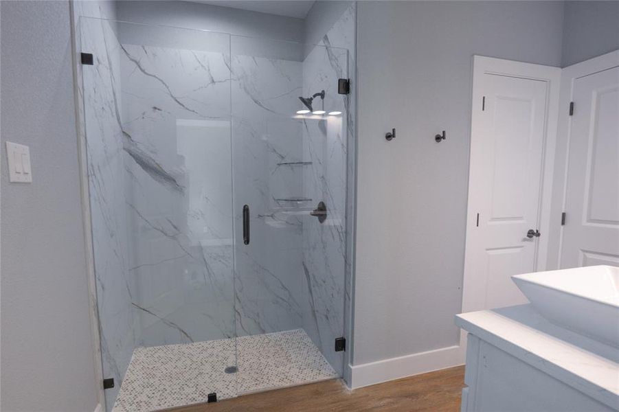 Full bath with a marble finish shower, vanity, and wood finished floors