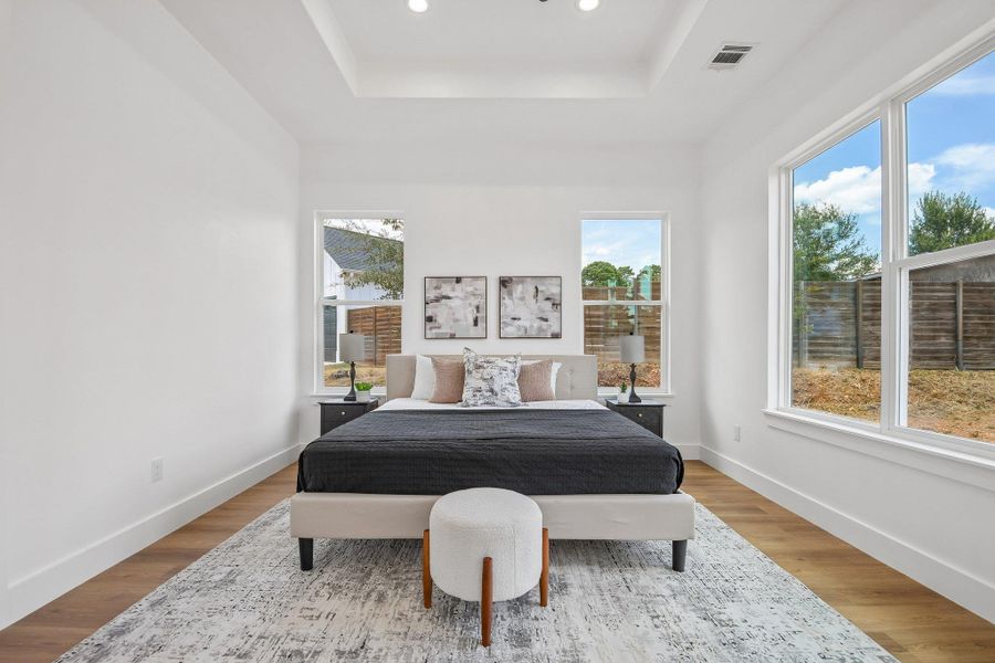 Hardwood floors and a tray ceiling define this minimalist bedroom overlooking the backyard. Hardwood floors and a tray ceiling define this minimalist bedroom overlooking the backyard.
