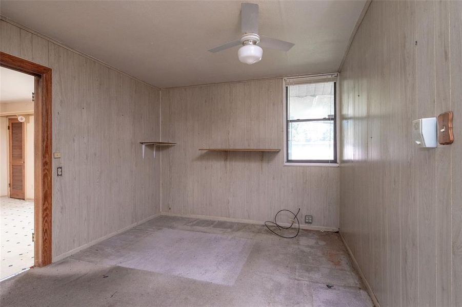 Empty room featuring wood walls and ceiling fan