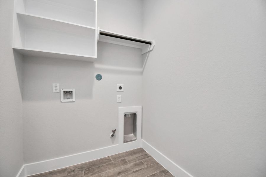 A perfect blend of functionality and comfort. Capture the essence of easy living with a first-floor laundry room, thoughtfully equipped with shelving for effortless organization. Both electric and gas connections available. Sample photo of completed home with similar floor plan. Actual colors and selections may vary.