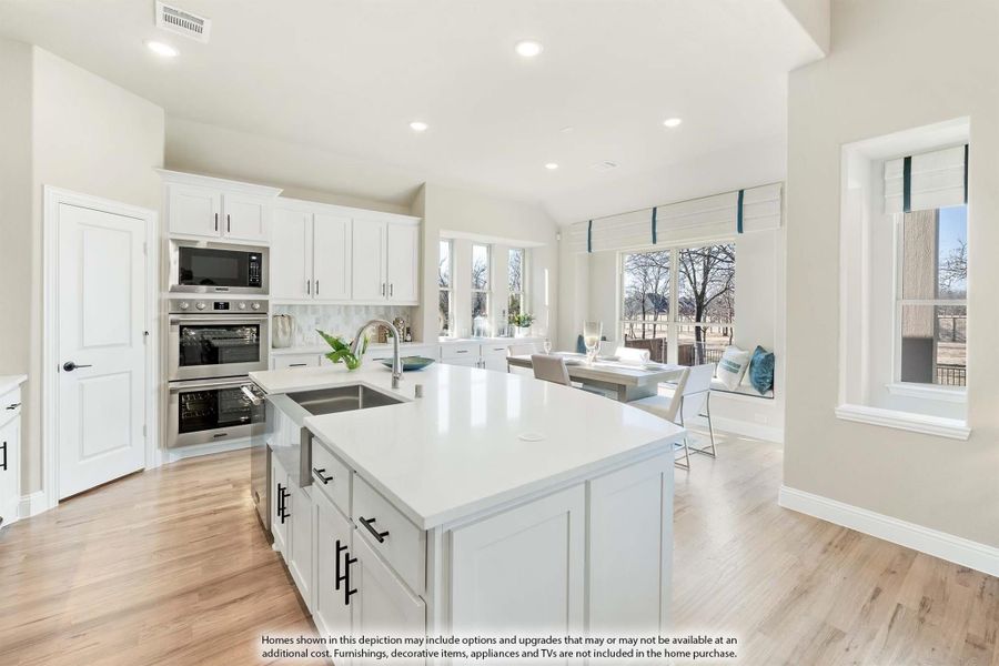 Open kitchen with white cabinets, center island, stainless steel appliances, and hardwood floors leading to a dining area. Open kitchen with white cabinets, center island, stainless steel appliances, and hardwood floors leading to a dining area.
