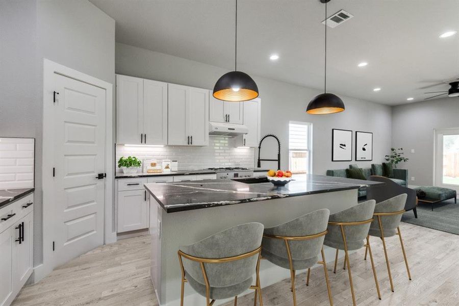 Kitchen with ceiling fan, tasteful backsplash, white cabinets, light hardwood / wood-style floors, and a kitchen island with sink