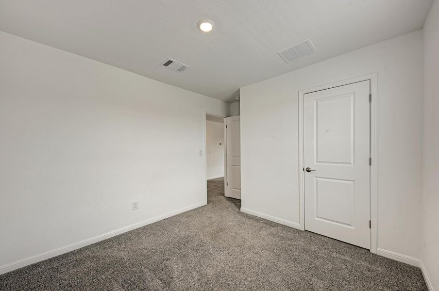 A well-lit room awaits your personal touch, featuring soft carpeting and a simple, clean aesthetic.