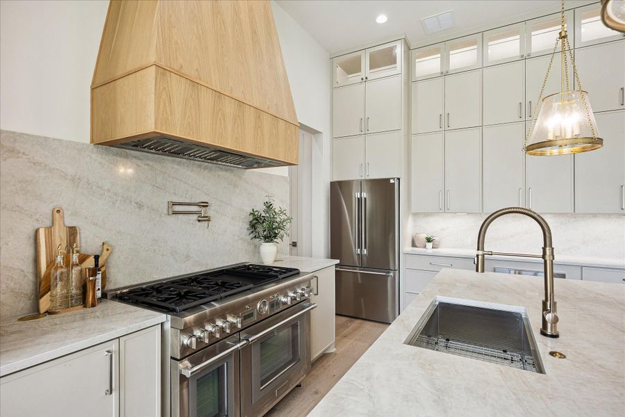 Thoughtful details are everywhere, from elegant Taj Mahal countertops and a seamless full slab backsplash to a Thermador luxury appliance package with a 48-inch commercial style gas range, custom vent hood, 36-inch built-in refrigerator, quiet dishwasher and microwave drawer. Custom floor to ceiling cabinetry, an oversized island and hidden pantry keep the kitchen both polished and practical, while a nearby mudroom adds another layer of everyday convenience.