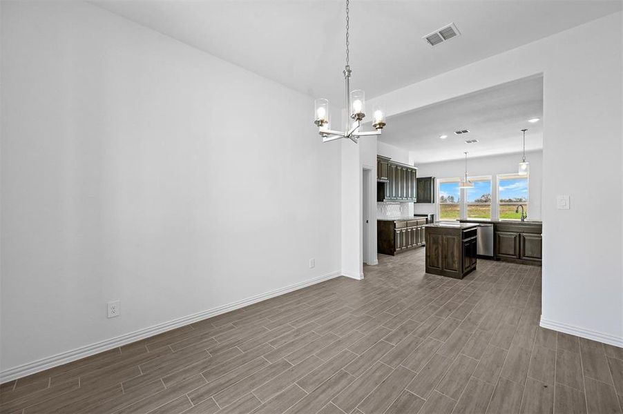 Kitchen featuring a kitchen island, wood-type flooring, sink, dark brown cabinetry, and a chandelier