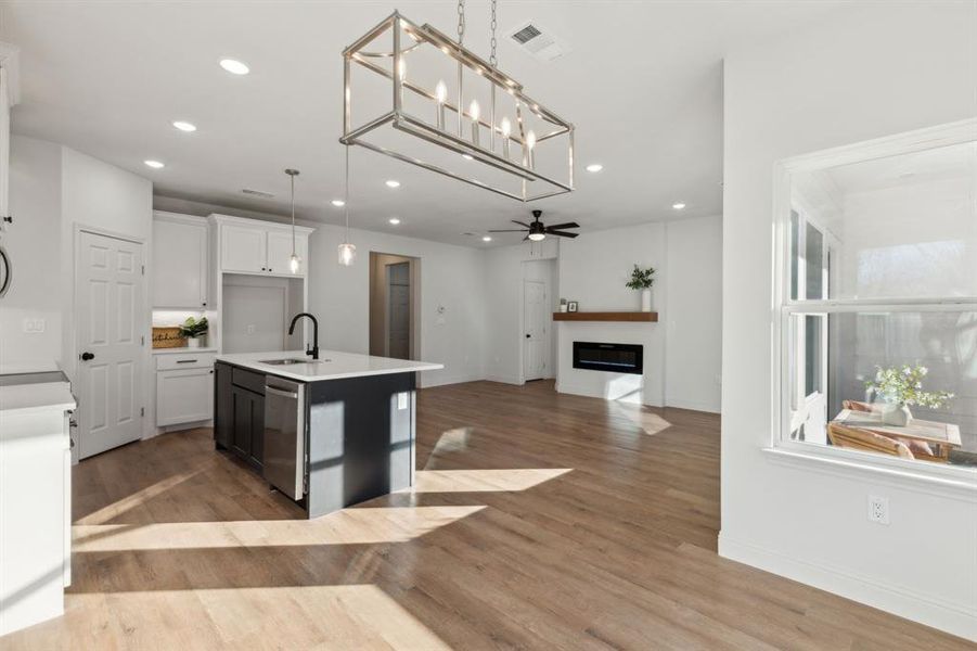 Kitchen featuring sink, hanging light fixtures, a kitchen island with sink, white cabinets, and ceiling fan with notable chandelier