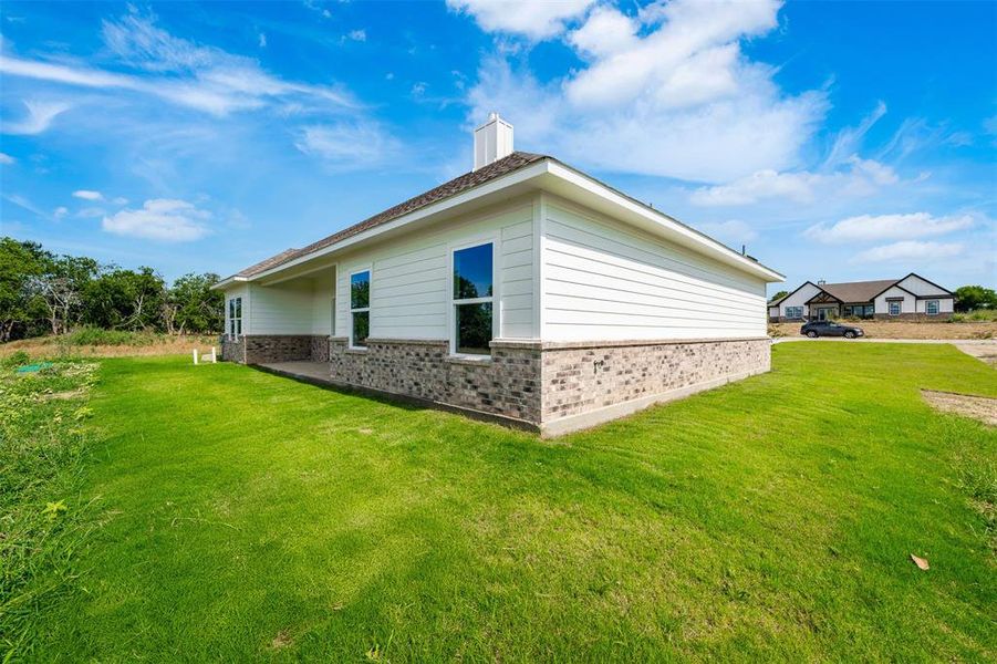 View of home's exterior with brick siding, a yard, and a chimney