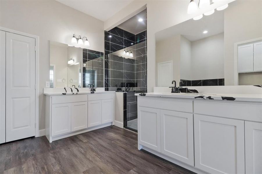 Bathroom with hardwood / wood-style flooring, vanity, a tile shower, and tile walls