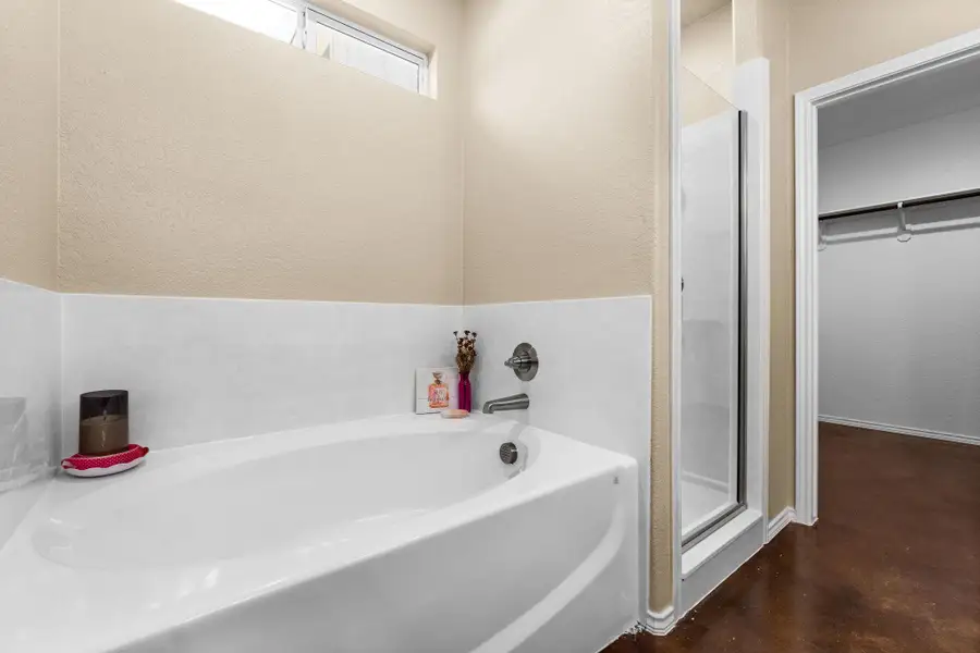 Full bath featuring a bath, a stall shower, a spacious closet, and concrete floors