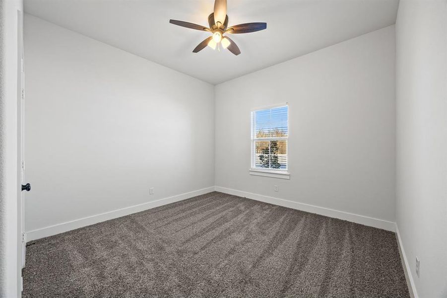 Empty room featuring dark carpet and a ceiling fan