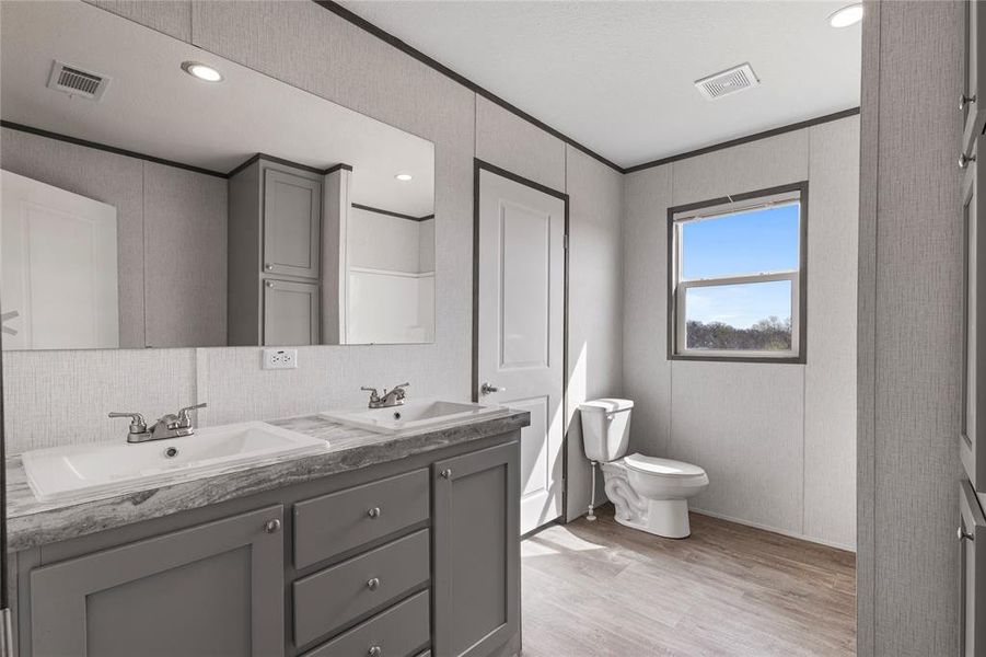 Bathroom featuring double vanity, crown molding, light wood-style floors, recessed lighting, and backsplash