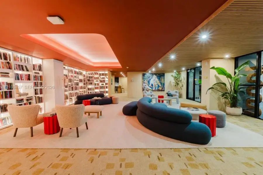 Floor-to-ceiling built-in bookcases with integrated lighting, recessed tray ceiling, wood-slat ceiling accent, and recessed lighting Floor-to-ceiling built-in bookcases with integrated lighting, recessed tray ceiling, wood-slat ceiling accent, and recessed lighting