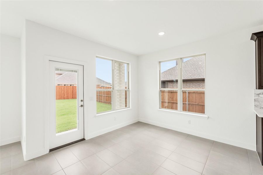 Bright breakfast nook with tile floors, back door, and two large windows overlooking fenced backyard Bright breakfast nook with tile floors, back door, and two large windows overlooking fenced backyard