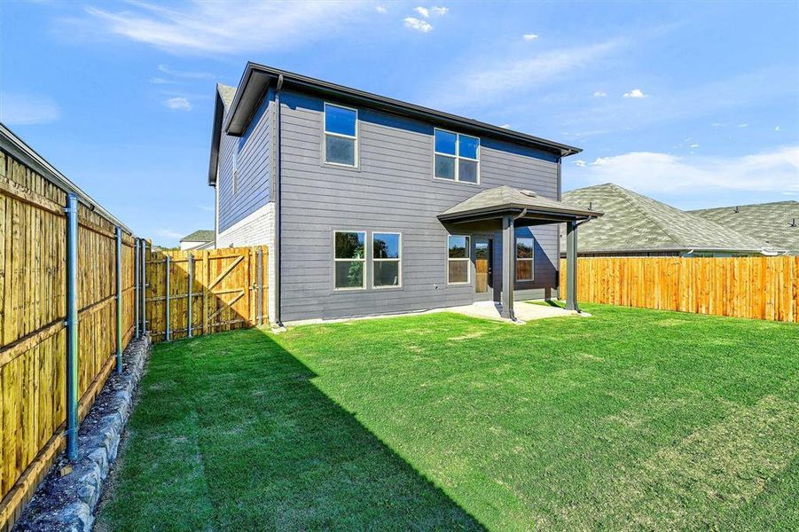 Rear view of property with a lawn and a patio area