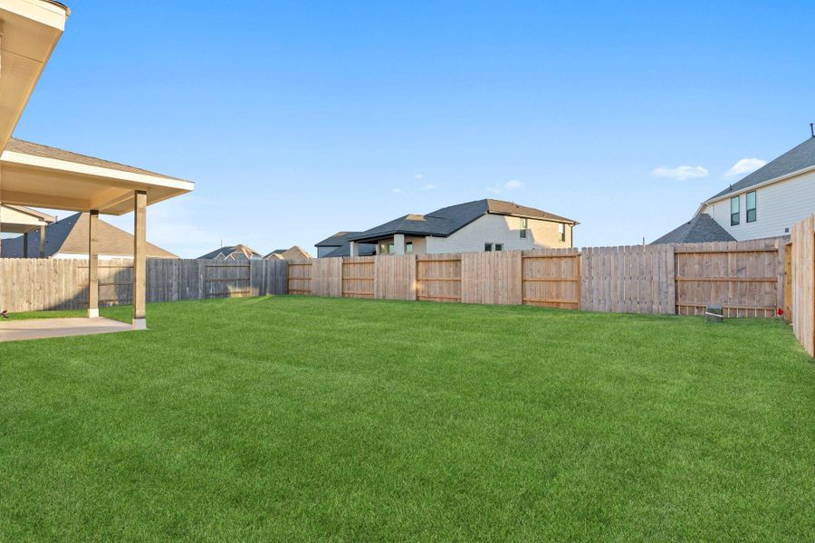 A view of the backyard reveals a wide, open lawn enclosed by a wooden privacy fence—ideal for outdoor activities, playtime, or future garden projects. A view of the backyard reveals a wide, open lawn enclosed by a wooden privacy fence—ideal for outdoor activities, playtime, or future garden projects.