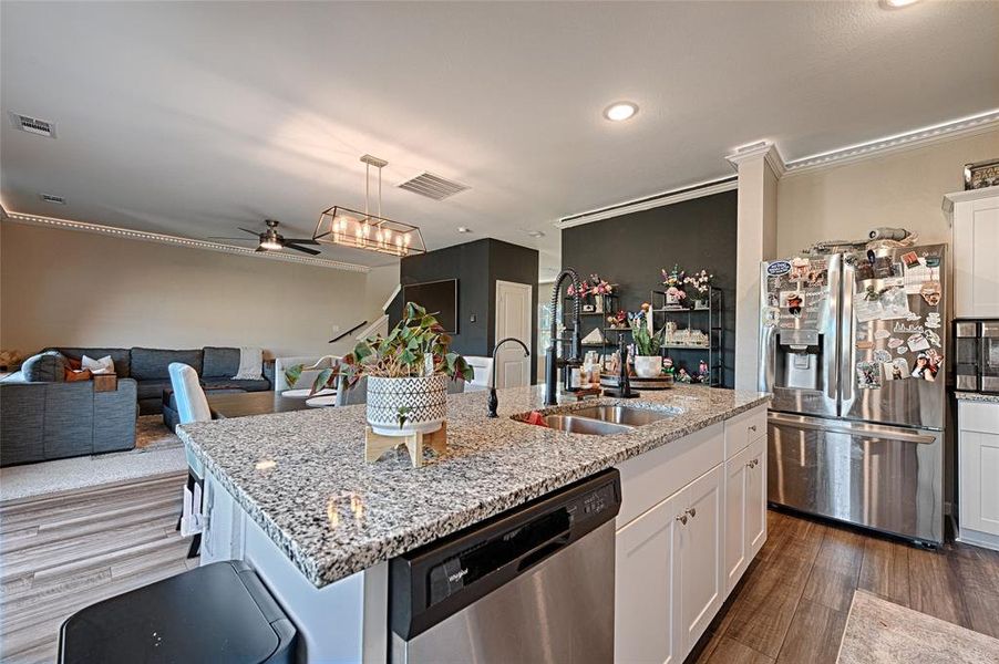 Kitchen with appliances with stainless steel finishes, white cabinets, crown molding, a ceiling fan, and dark wood finished floors Kitchen with appliances with stainless steel finishes, white cabinets, crown molding, a ceiling fan, and dark wood finished floors