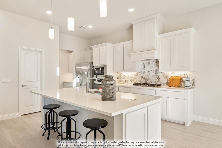 Kitchen with white cabinets, large island with three bar stools, patterned tile backsplash, and stainless steel appliances