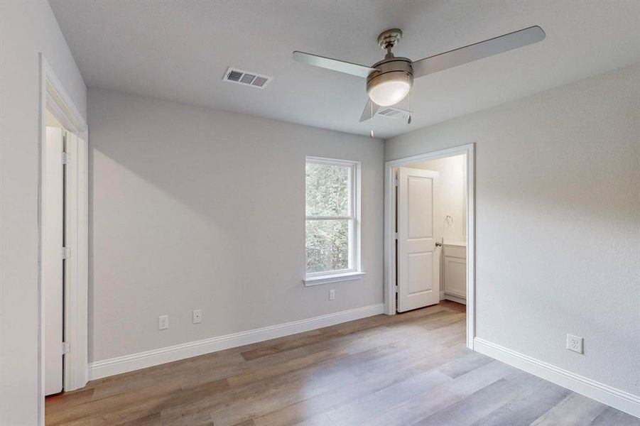 Unfurnished bedroom featuring light wood-type flooring, connected bathroom, and ceiling fan