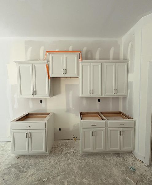 Unfinished interior space featuring white shaker-style cabinetry with chrome hardware, offering ample storage Unfinished interior space featuring white shaker-style cabinetry with chrome hardware, offering ample storage