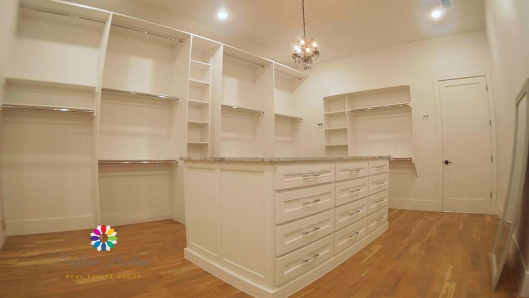 Spacious closet featuring hardwood / wood-style flooring and a chandelier