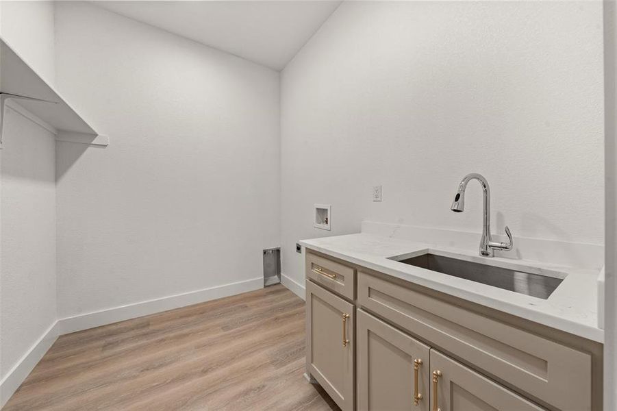 Washroom with light wood-style flooring, hookup for a washing machine, and cabinet space Washroom with light wood-style flooring, hookup for a washing machine, and cabinet space