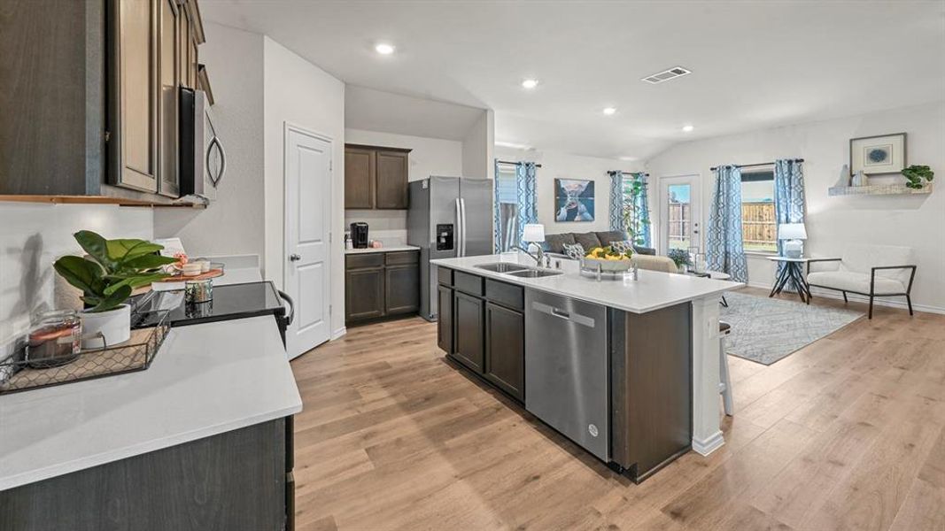 Kitchen with a kitchen island with sink, stainless steel appliances, light wood-style flooring, recessed lighting, and dark wood finish cabinetry