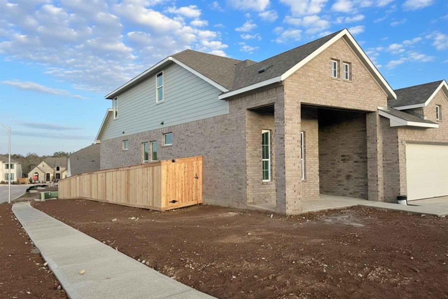 View of side of property with brick siding, a residential view, a garage, and roof with shingles