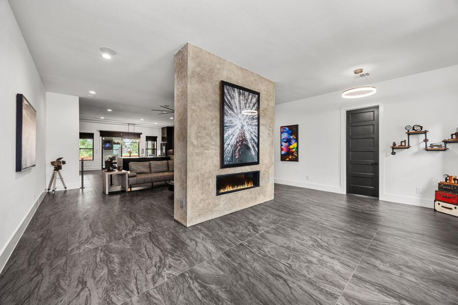 This modern living space features sleek, dark flooring and a stylish partition with built-in fireplace. The open layout leads to a cozy seating area and kitchen, offering a contemporary and welcoming atmosphere. This modern living space features sleek, dark flooring and a stylish partition with built-in fireplace. The open layout leads to a cozy seating area and kitchen, offering a contemporary and welcoming atmosphere.