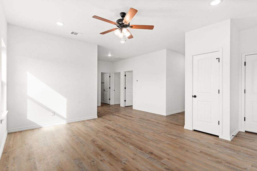 Empty room featuring visible vents, ceiling fan, recessed lighting, and wood finished floors Empty room featuring visible vents, ceiling fan, recessed lighting, and wood finished floors