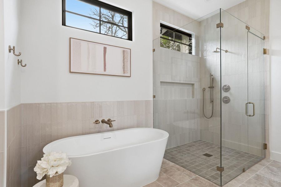 Bathroom featuring a stall shower, a soaking tub, tile walls, and a wainscoted wall