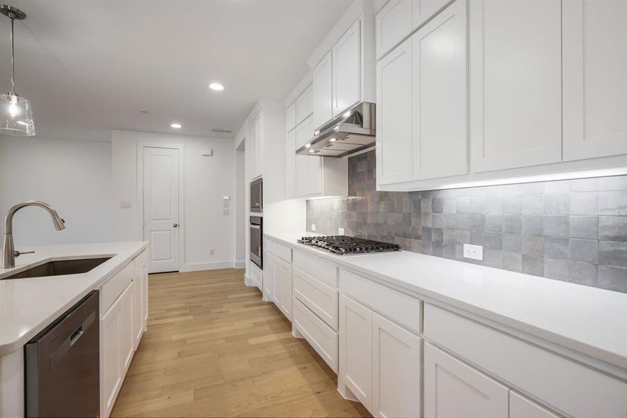 Modern kitchen featuring light wood-finish flooring and white shaker-style cabinetry