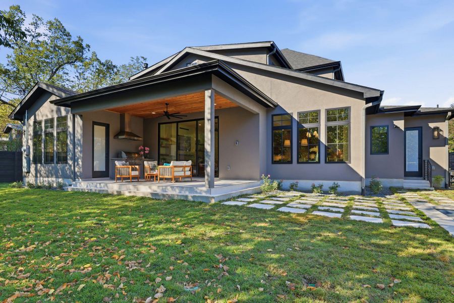 Rear view of house featuring ceiling fan, a patio area, stucco siding, and a yard