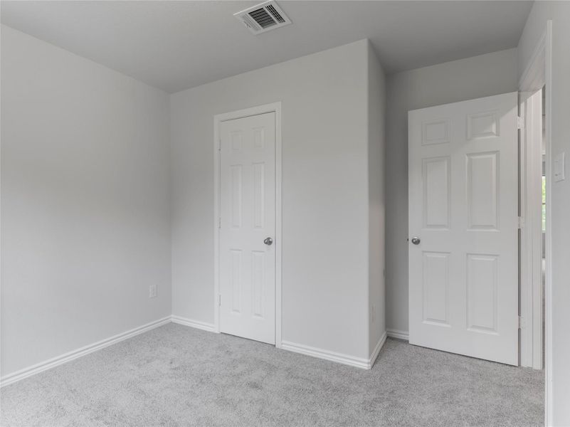 A cozy upstairs bedroom featuring plush carpeting.